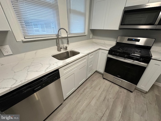 kitchen with light stone counters, sink, white cabinetry, and stainless steel appliances