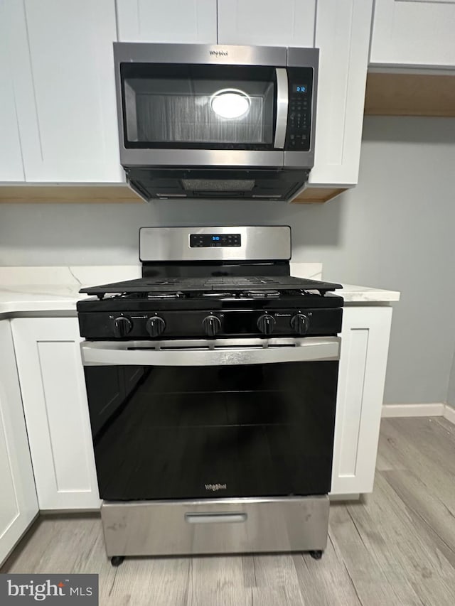 kitchen featuring appliances with stainless steel finishes, light hardwood / wood-style floors, and white cabinetry