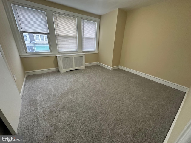 empty room with carpet floors and radiator heating unit