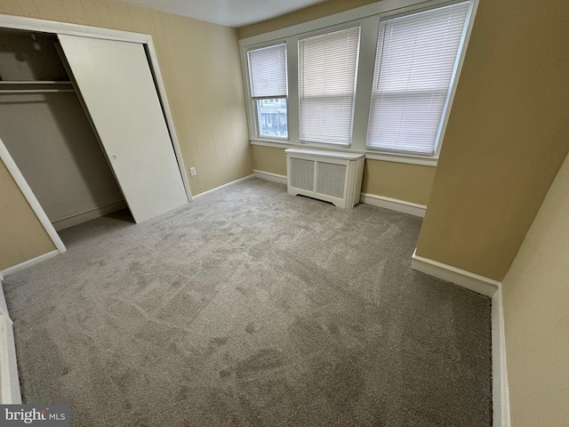 unfurnished bedroom featuring light carpet, radiator, and a closet