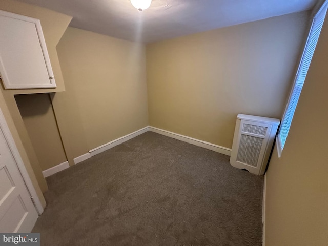 unfurnished room with dark colored carpet and heating unit