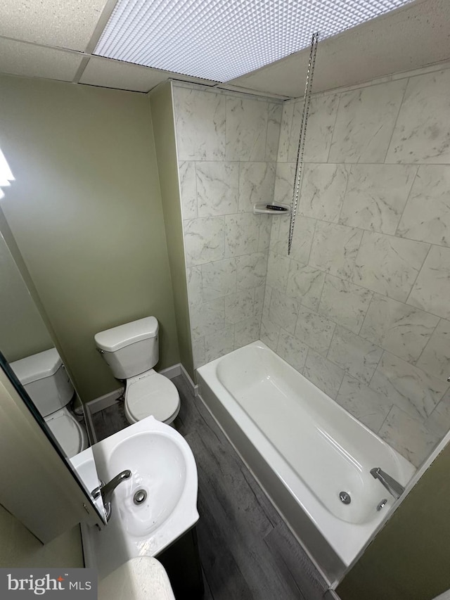 bathroom featuring toilet, a drop ceiling, and sink