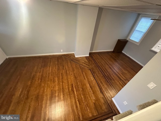 empty room featuring wood-type flooring and a drop ceiling