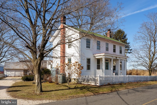 view of front facade featuring a fenced front yard, a chimney, and cooling unit