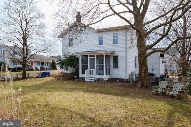 view of front of property with a chimney, entry steps, a sunroom, fence, and a front lawn