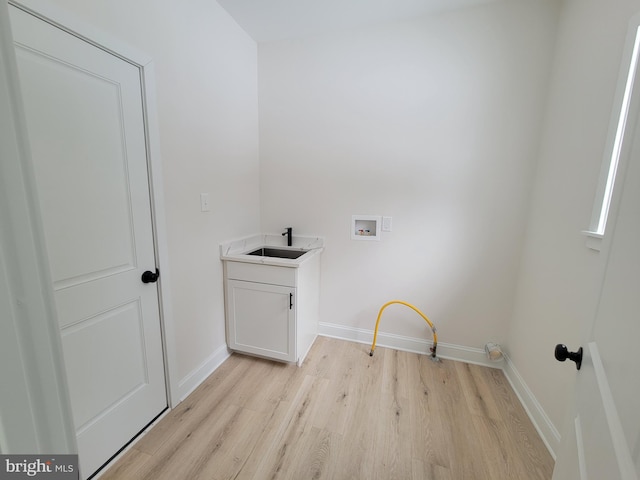 laundry area featuring hookup for a washing machine, a sink, baseboards, light wood-type flooring, and cabinet space