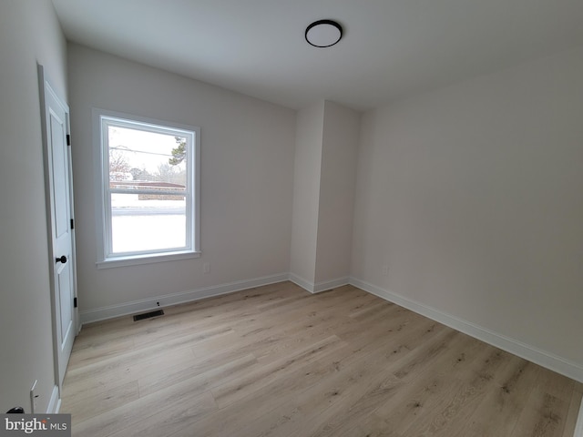 empty room featuring light wood-style flooring, visible vents, and baseboards