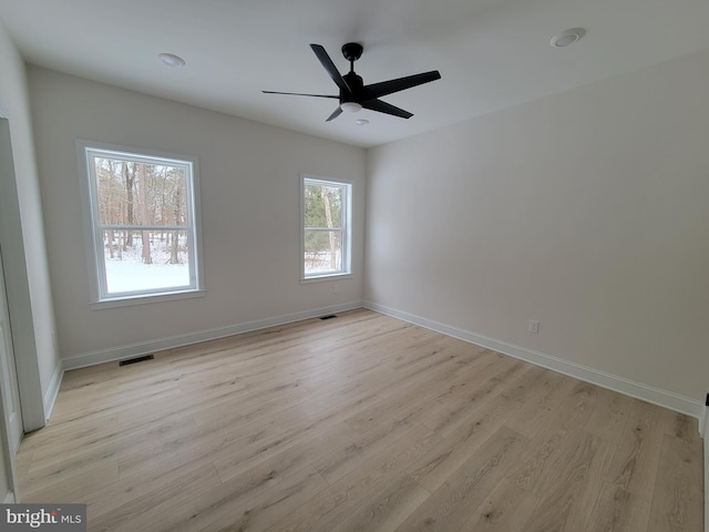 unfurnished room with light wood-style floors, visible vents, baseboards, and a ceiling fan