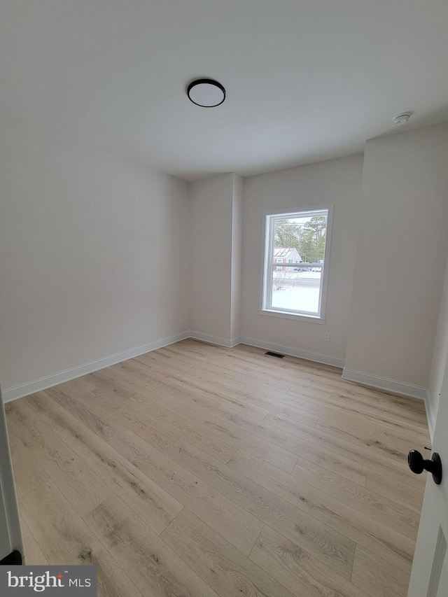 spare room with baseboards, visible vents, and light wood finished floors