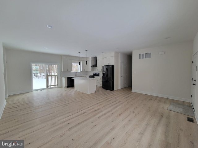 kitchen featuring open floor plan, black fridge with ice dispenser, visible vents, and a center island