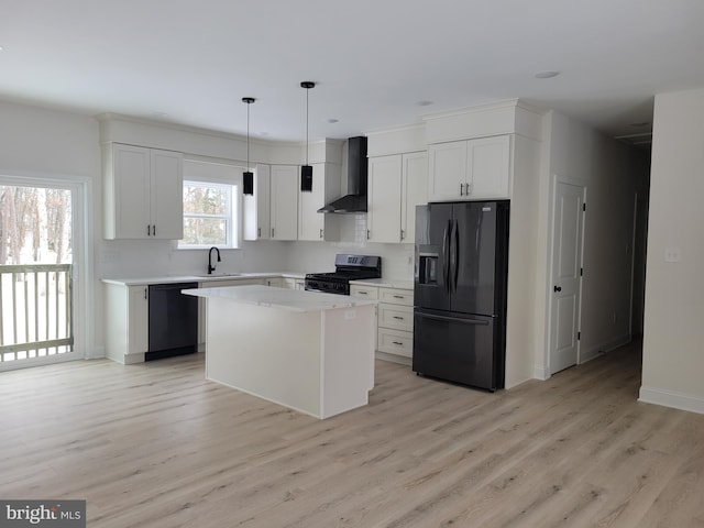 kitchen featuring a sink, black appliances, light wood-type flooring, and wall chimney range hood