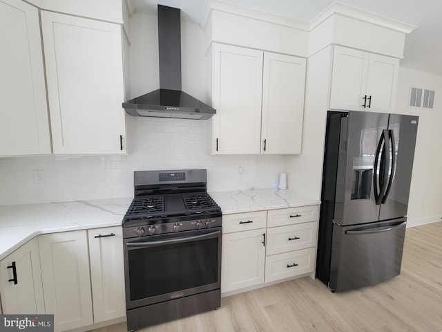 kitchen featuring stainless steel range with gas cooktop, visible vents, light wood-style floors, refrigerator with ice dispenser, and wall chimney exhaust hood