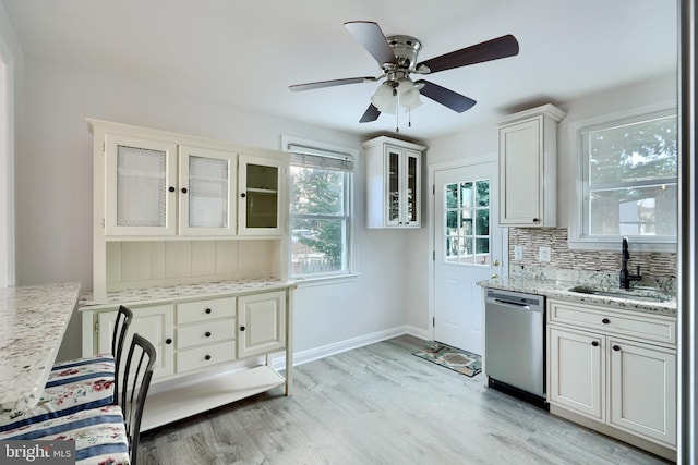 kitchen featuring stainless steel dishwasher, light stone countertops, sink, and tasteful backsplash