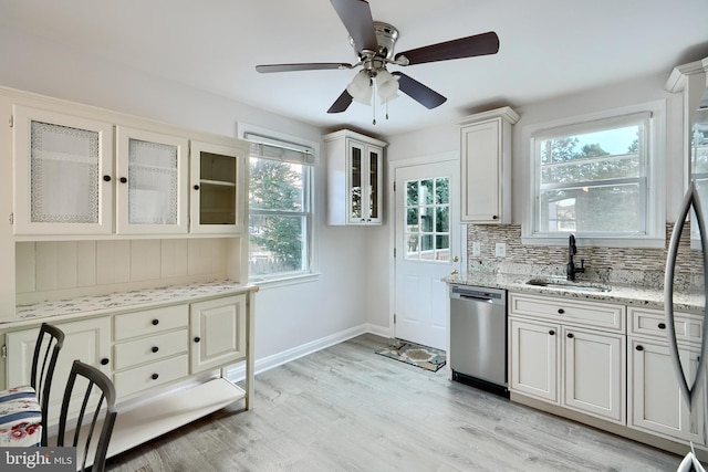 kitchen featuring white cabinetry, tasteful backsplash, stainless steel dishwasher, light stone counters, and sink