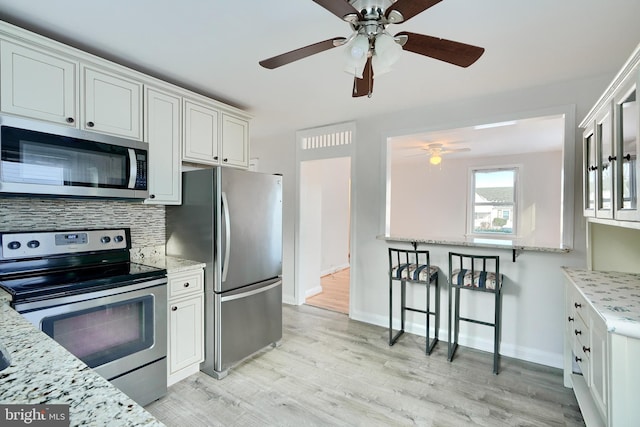 kitchen featuring stainless steel appliances, decorative backsplash, light hardwood / wood-style floors, and white cabinets