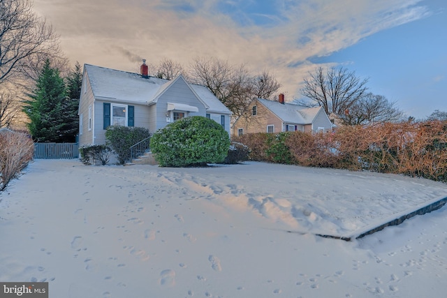 snow covered property featuring fence and a chimney