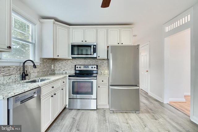 kitchen featuring appliances with stainless steel finishes, sink, light stone counters, and white cabinetry