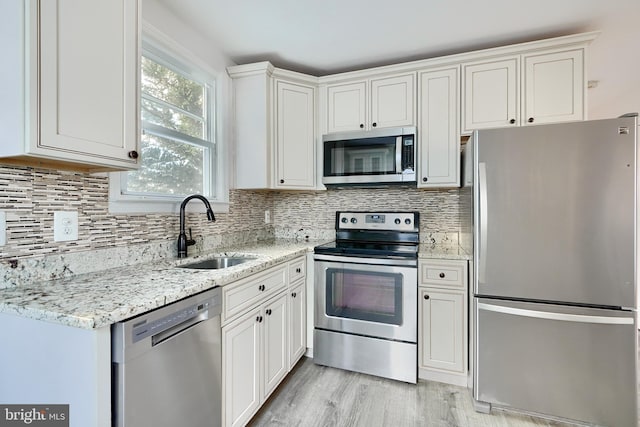 kitchen featuring light stone counters, sink, white cabinetry, and appliances with stainless steel finishes