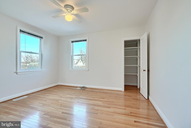 unfurnished bedroom featuring ceiling fan, a closet, light hardwood / wood-style floors, and multiple windows