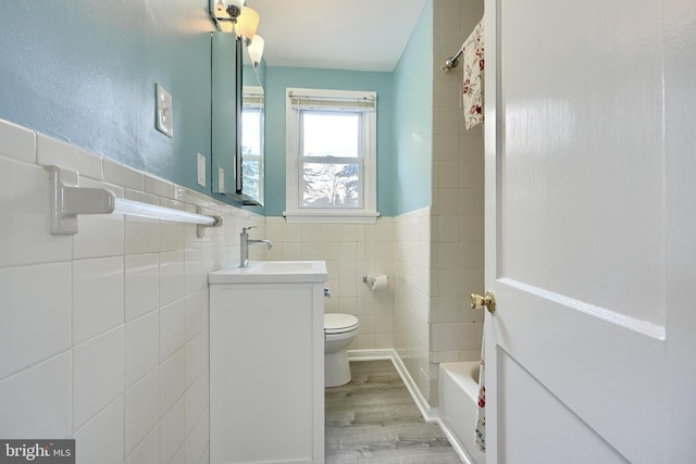 full bathroom featuring toilet, shower / bath combination, hardwood / wood-style flooring, tile walls, and vanity