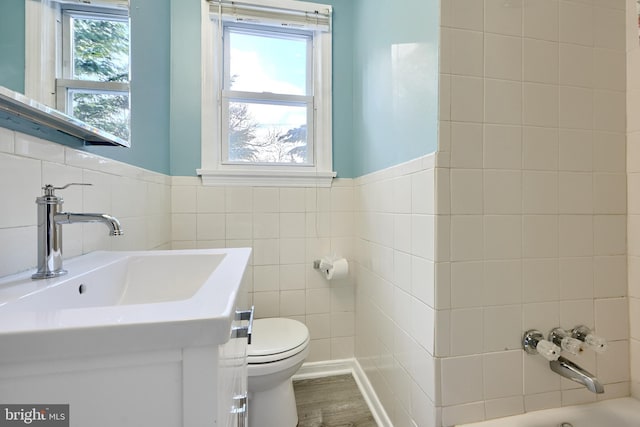 bathroom featuring toilet, a bathing tub, tile walls, wood-type flooring, and vanity