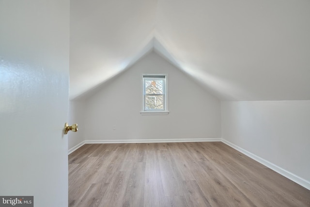 additional living space with light hardwood / wood-style floors and vaulted ceiling