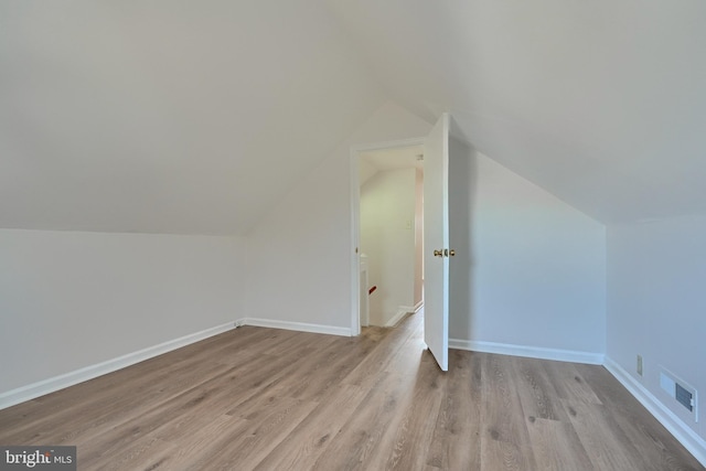 additional living space featuring vaulted ceiling and light hardwood / wood-style floors