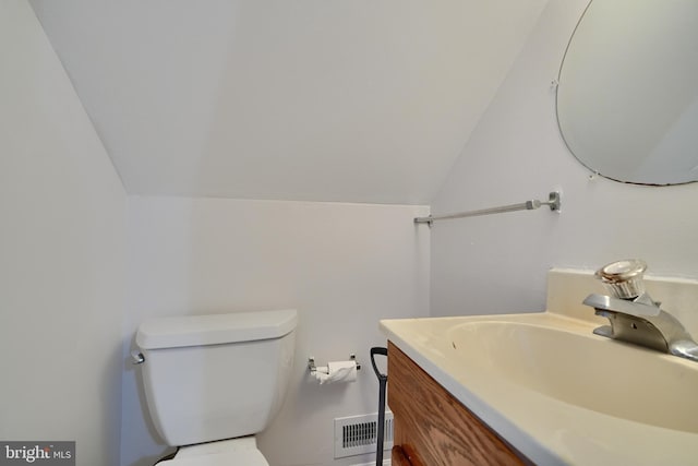 bathroom featuring lofted ceiling, vanity, and toilet