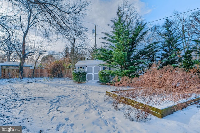 yard layered in snow featuring a shed