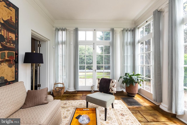 sunroom with ornate columns, crown molding, french doors, and wood finished floors