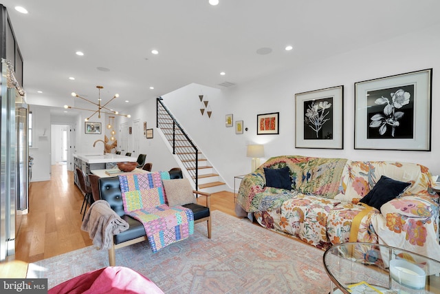 living room featuring a notable chandelier, sink, and light hardwood / wood-style floors