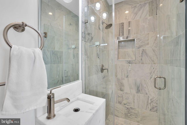 bathroom featuring a shower with shower door and vanity