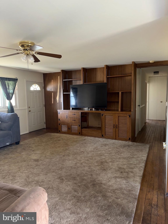 unfurnished living room featuring ceiling fan and dark wood-style flooring