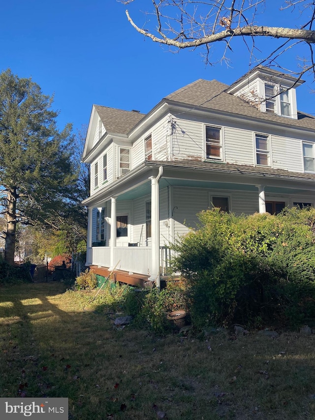 view of property exterior with a yard and a porch