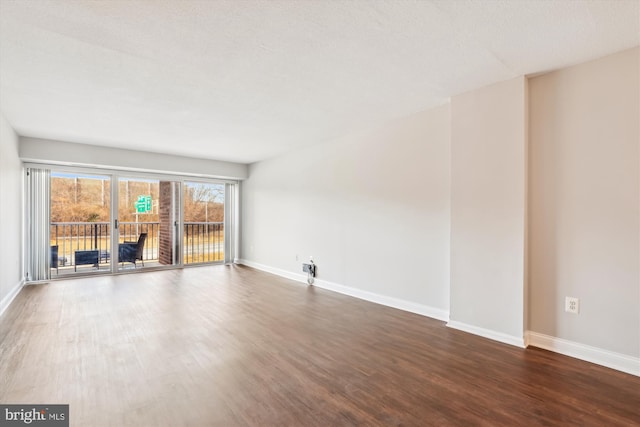 empty room with a textured ceiling and dark hardwood / wood-style flooring