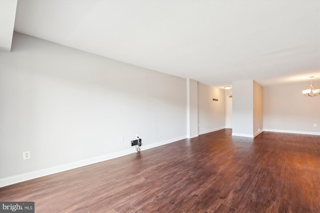 empty room with an inviting chandelier and dark hardwood / wood-style flooring