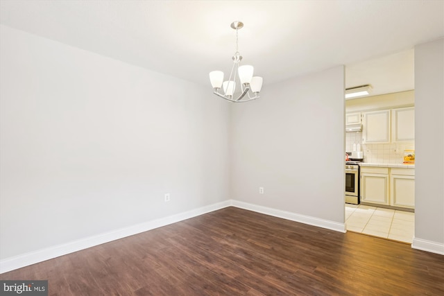 empty room with a notable chandelier and dark hardwood / wood-style floors