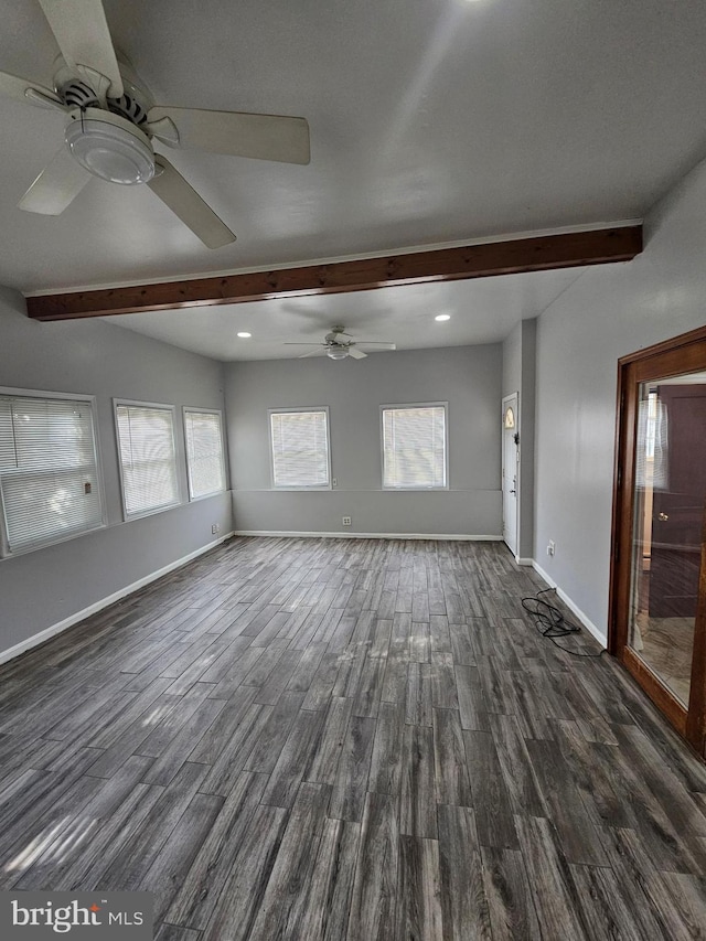 unfurnished living room featuring a wealth of natural light, beam ceiling, and dark hardwood / wood-style flooring