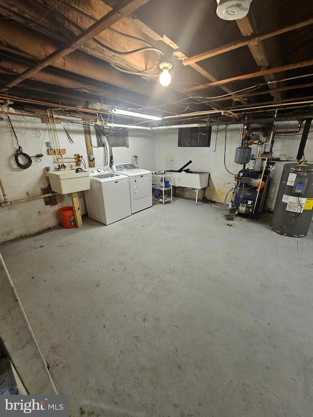 basement featuring sink, electric water heater, and independent washer and dryer