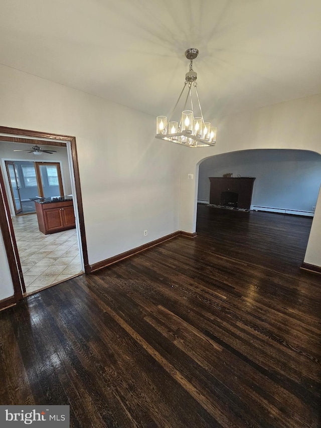 unfurnished dining area with a chandelier, a baseboard radiator, and wood-type flooring