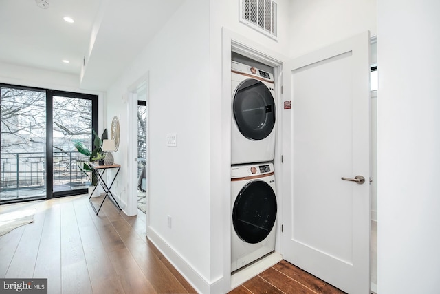 laundry room featuring dark hardwood / wood-style floors and stacked washer and clothes dryer