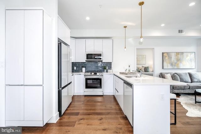 kitchen featuring decorative light fixtures, kitchen peninsula, a kitchen breakfast bar, stainless steel appliances, and white cabinets