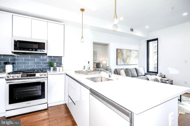 kitchen featuring hanging light fixtures, kitchen peninsula, stainless steel range with gas stovetop, and white cabinetry