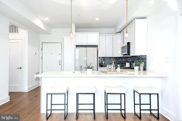 kitchen with pendant lighting, white cabinetry, light hardwood / wood-style floors, a kitchen breakfast bar, and kitchen peninsula