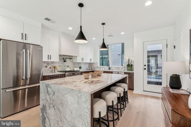 kitchen with white cabinetry, pendant lighting, stainless steel appliances, and a kitchen island