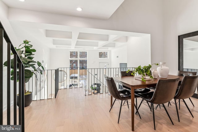 dining space featuring beam ceiling, coffered ceiling, and light hardwood / wood-style flooring