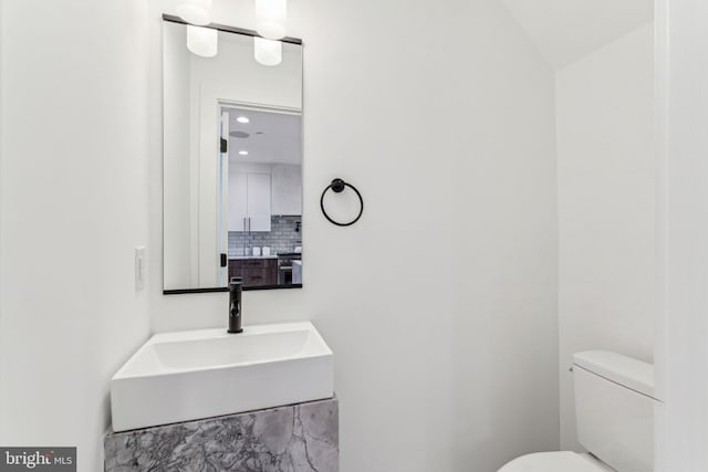 bathroom featuring sink, toilet, and tasteful backsplash