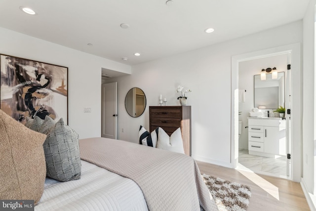 bedroom featuring ensuite bath and light wood-type flooring