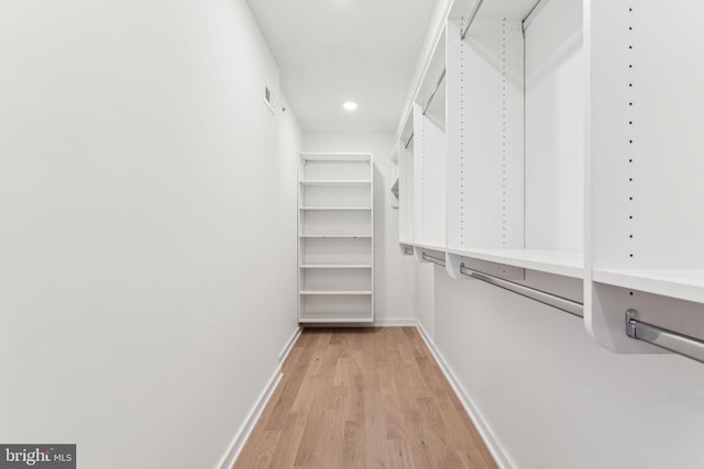 walk in closet with light hardwood / wood-style flooring