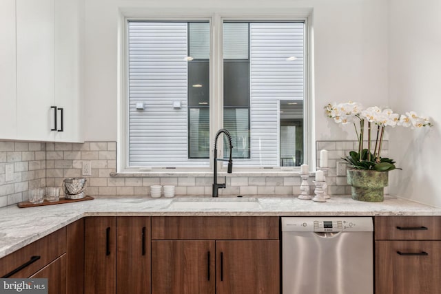 kitchen featuring light stone countertops, sink, white cabinetry, and stainless steel dishwasher